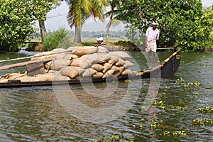 Allepey, Kerala, India Ã¢â¬â March 31, 2015: Indian man transport dwell with rice for boats. backwaters canoe in state